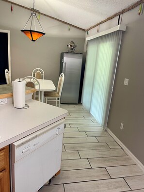 A compact kitchen with a dining area, a refrigerator, and a hanging light fixture. - Coastal escape near New Smyrna Beach (Edgewater)