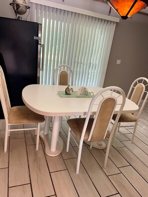 A dining area with a round table, four chairs, a globe on a shelf, and a window with blinds. - Coastal escape near New Smyrna Beach (Edgewater)