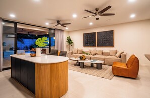 A modern living room with a central island, a sofa, a coffee table, and a dining area. - Villa LaLa Land • 5 BR House with private pool (Jaco)