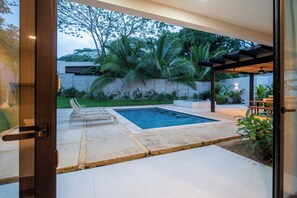 A modern outdoor pool area with a rectangular pool, lounge chairs, and a pergola. - Villa LaLa Land • 5 BR House with private pool (Jaco)