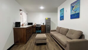 Un espacio habitable funcional con kitchenette, un sofá y dos cuadros colgados en la pared.