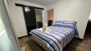 Un dormitorio con cama, puerta corredera, televisor y una mesita.