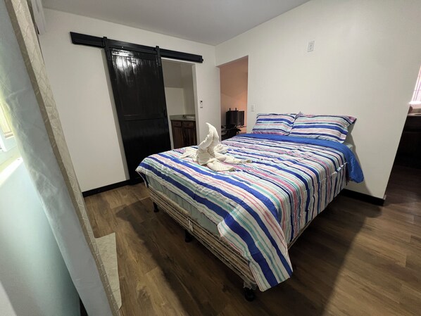 Un dormitorio con cama, puerta corredera, televisor y una mesita.