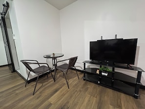 A modern living room with a flat-screen TV, two chairs, a small round table, and a wooden floor. - Raul Villas  Hotel & Hostal  (Coxen Hole)
