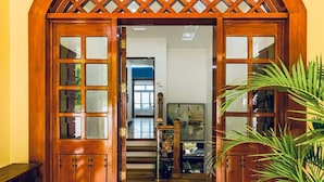 A wooden entrance with a lattice design, leading to an interior space with a staircase and a television. - Monk Punta Fuego Beach House Nasugbu (Nasugbu)