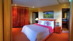 A hotel room with a large bed, two bedside lamps, a painting on the wall, and a wooden wardrobe. - Monk Punta Fuego Beach House Nasugbu (Nasugbu)