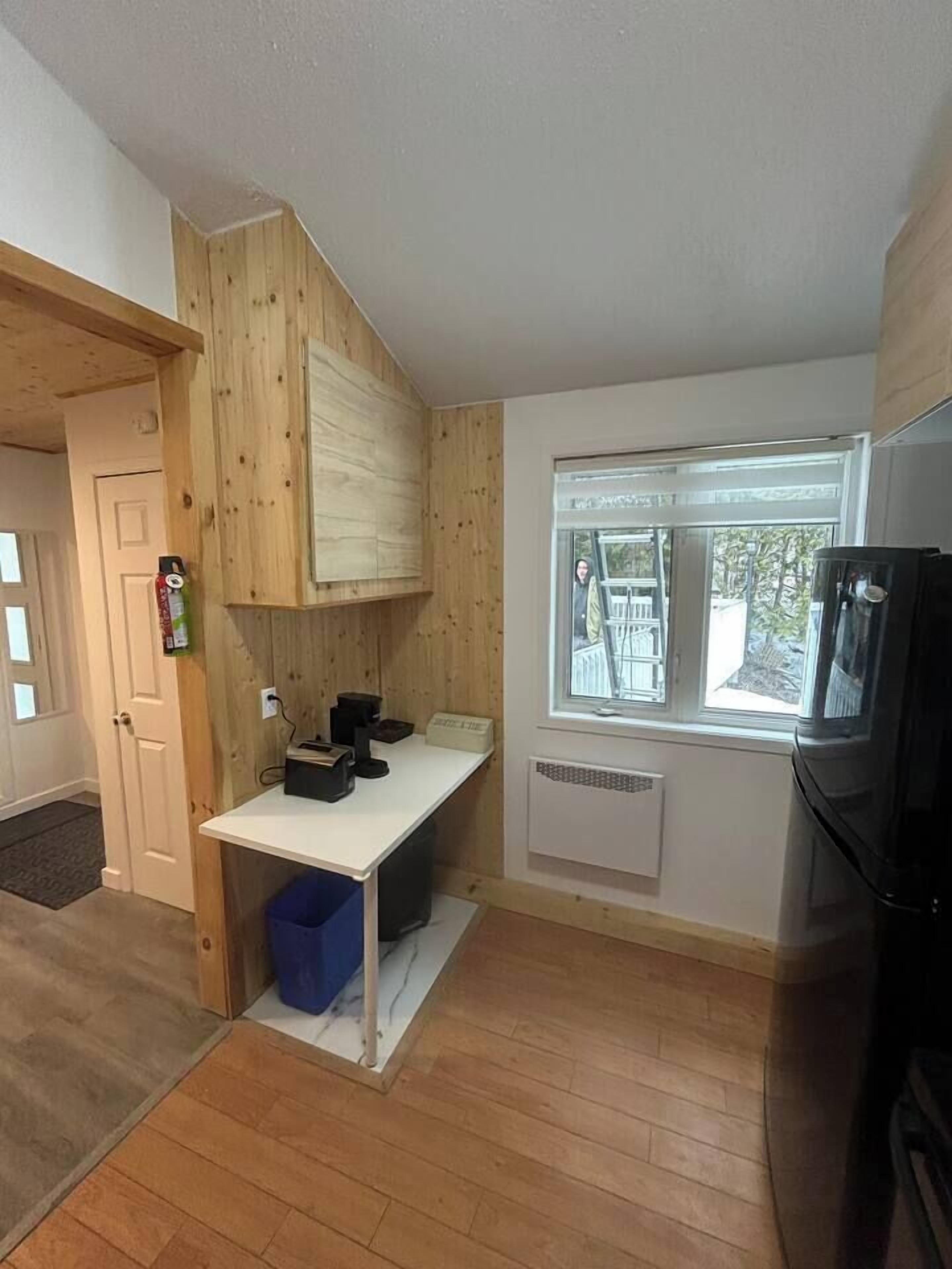 Een kleine keuken met een inbouwfornuis, een raam met uitzicht en een deur naar een andere kamer.