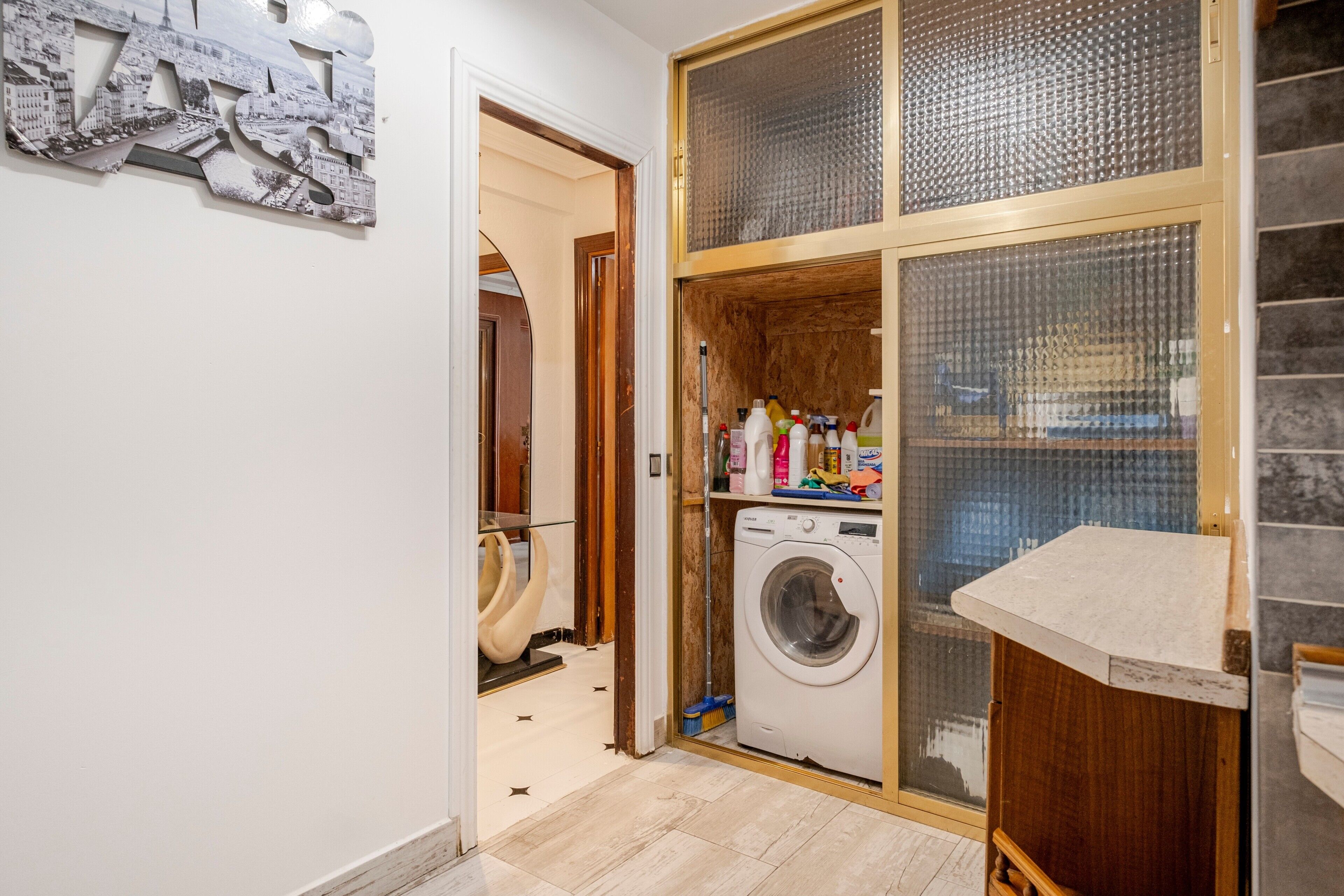 Een wasruimte met een wasmachine, een droogrek en een plank met schoonmaakmiddelen.