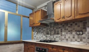 A kitchen with wooden cabinets, a gas stove, and a tiled backsplash.