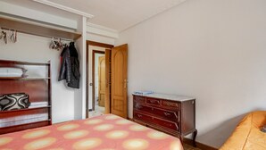 A bedroom with a bed, a dresser, a wardrobe, and a door leading to another room.