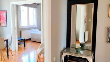 Une pièce comprenant un lit, un bureau, des chaises, un miroir et des œuvres d’art accrochées aux murs.