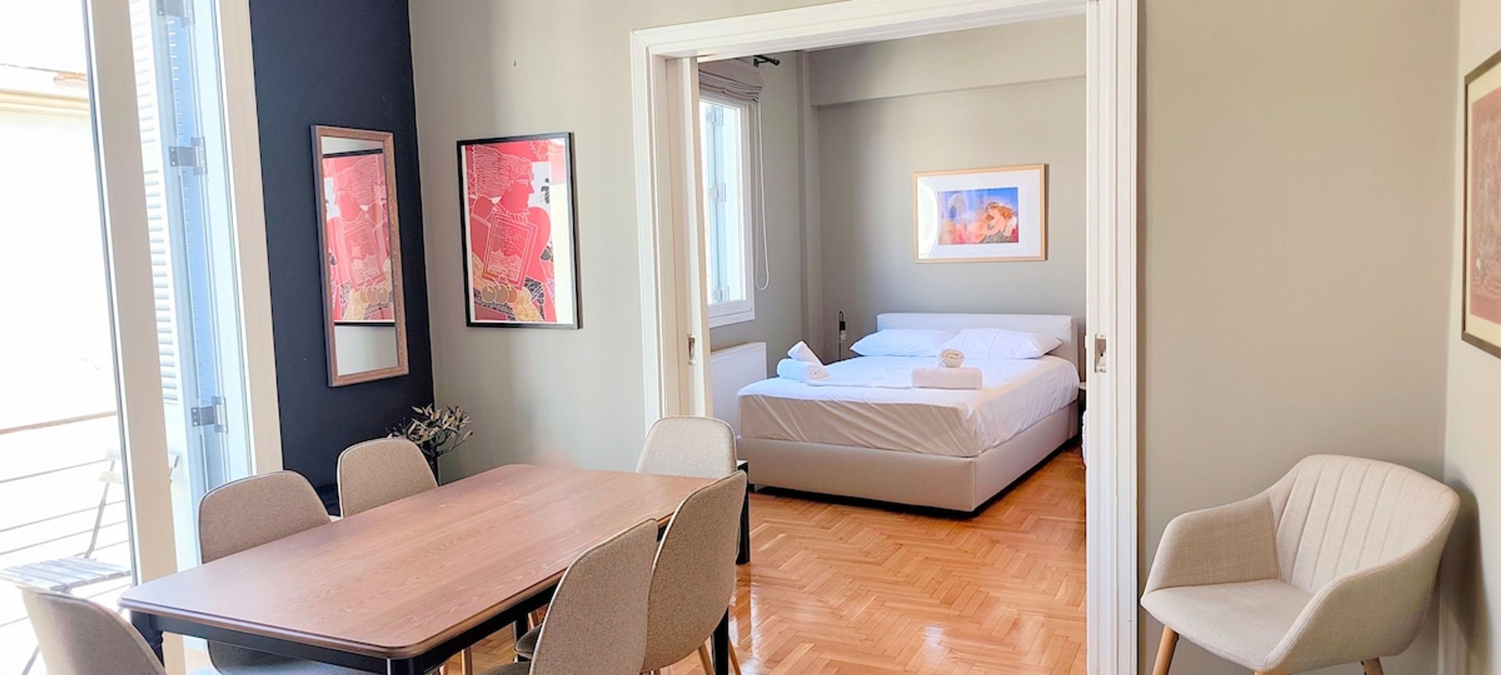 Une chambre d’hôtel avec un lit, une table et des chaises. Deux œuvres d’art encadrées sont accrochées au mur.
