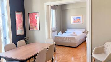 Une chambre d’hôtel avec un lit, une table et des chaises. Deux œuvres d’art encadrées sont accrochées au mur.