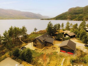 A lakeside property with a main house, a guest house, and a dock with surfboards.