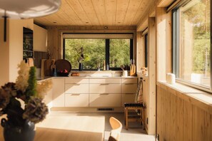 Una cocina moderna con armarios de madera, un ventanal grande y un comedor con una silla.