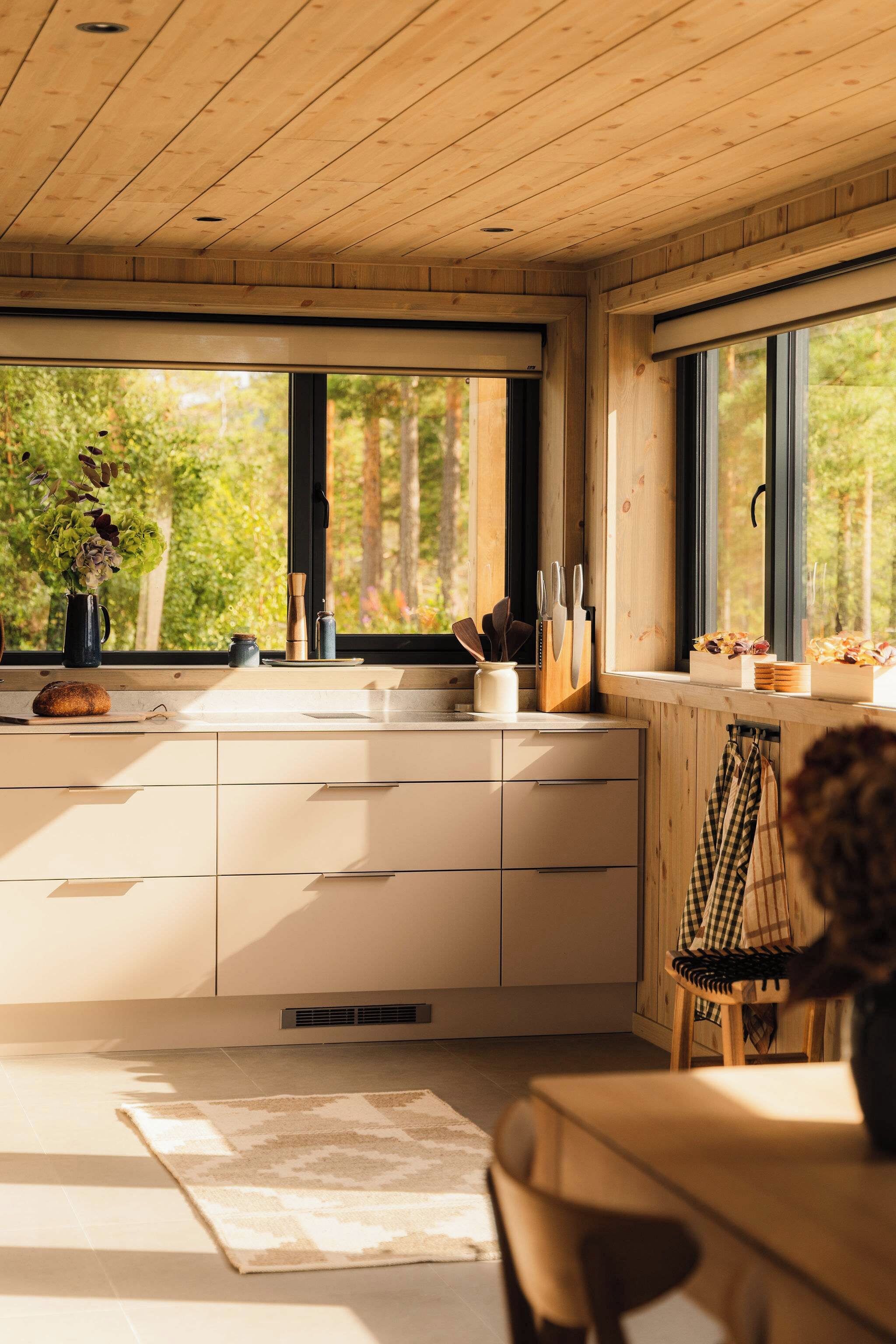 Une cuisine moderne avec des meubles en bois, une grande fenêtre et une vue sur la verdure environnante.