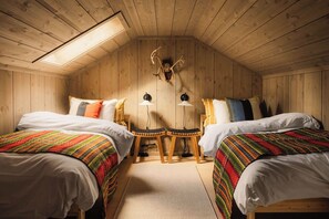 Una habitación acogedora con dos camas, techo de madera y una decoración con cabeza de ciervo.