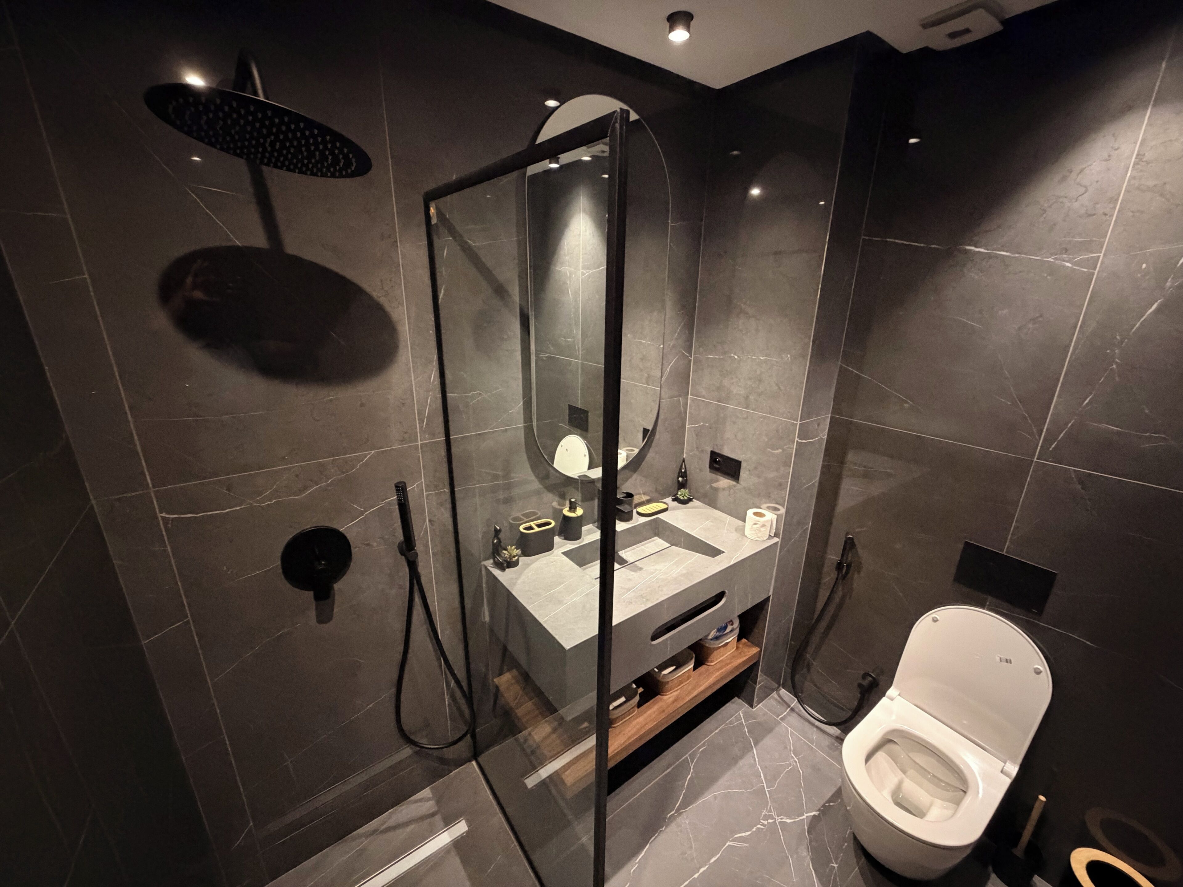 Un baño moderno con ducha envuelta en cristal, inodoro y tocador con espejo.