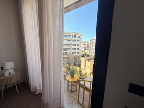 Un balcó amb una taula groga i una planta en test, amb vista a un paisatge urbà amb edificis diversos.