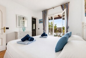 A bedroom with a large bed, a dresser, a mirror, and a view of the outdoors. - Villa La Goleta by 3 Villas Menorca (Cala Llonga)