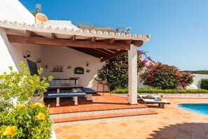 A covered outdoor area with a pool, a table, and chairs. - Villa La Goleta by 3 Villas Menorca (Cala Llonga)