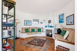 A living room with a sofa set, a fireplace, a rug, and a bookshelf. - Villa La Goleta by 3 Villas Menorca (Cala Llonga)