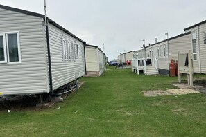 A row of mobile homes with a grassy area in between. - Caravan Sleeps 8 With Sea Views and Parking (Morecambe)