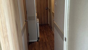 A hallway with wooden flooring, white walls, and a door at the end. - Caravan Sleeps 8 With Sea Views and Parking (Morecambe)