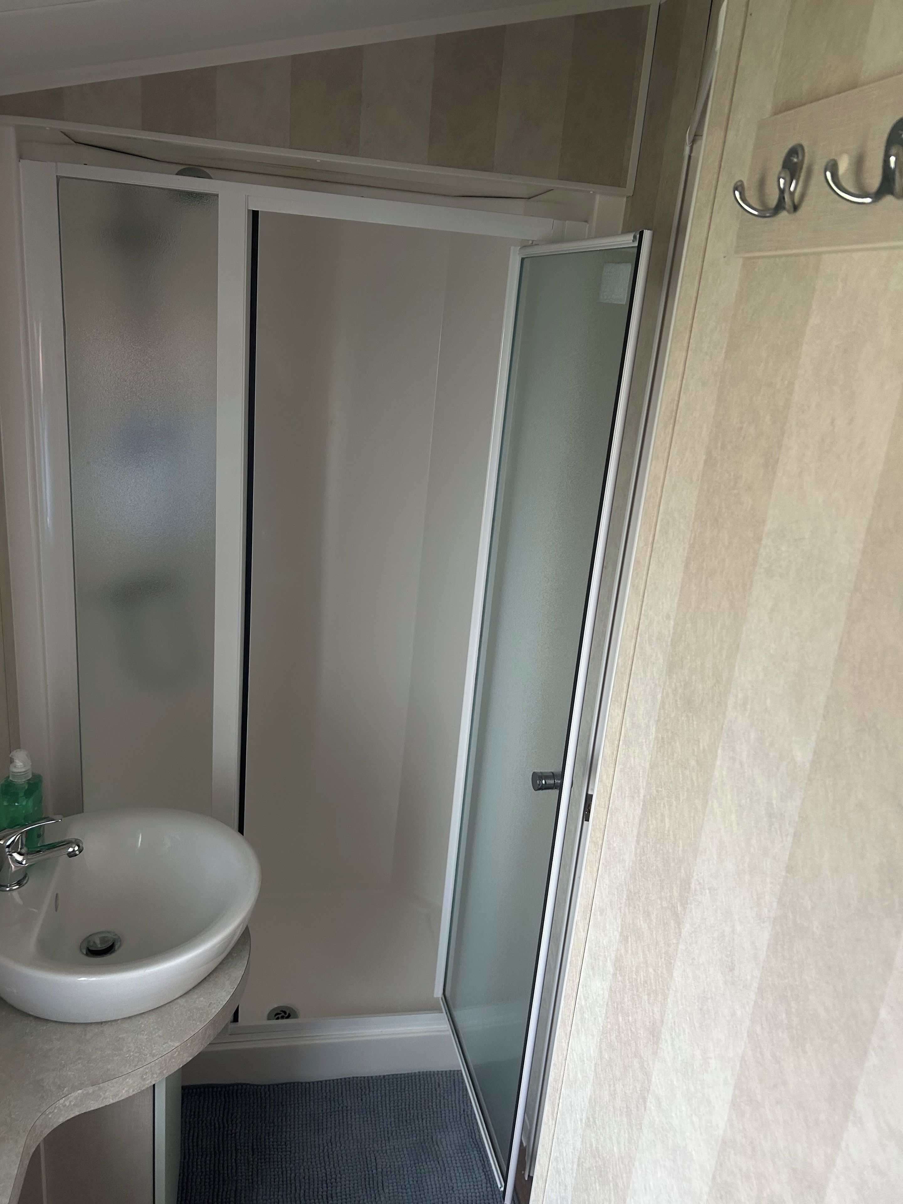 A bathroom with a white sink, a glass shower enclosure, and a towel rack.