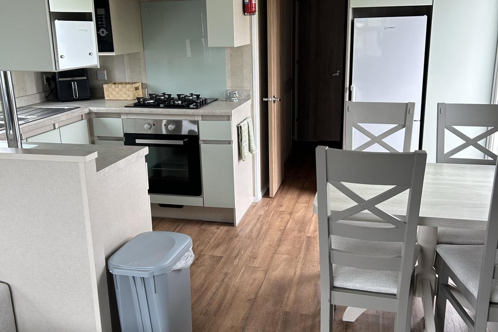 A compact kitchen with a gas stove, oven, and a small trash bin.