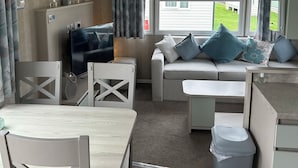 Una sala de estar acogedora con un sofá, una televisión y una mesa de comedor con sillas.