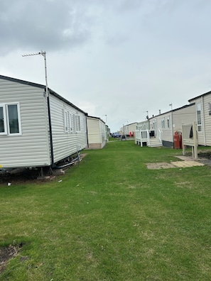 Una fila de casas móviles con un césped entre ellas.