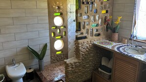 A bathroom with a stone wall, a sink, and a toilet.