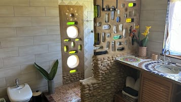 Une salle de bain avec un mur en pierre, un lavabo et des toilettes.