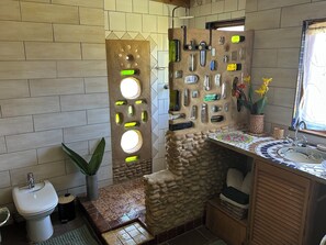 A bathroom with a stone wall, a sink, and a toilet.