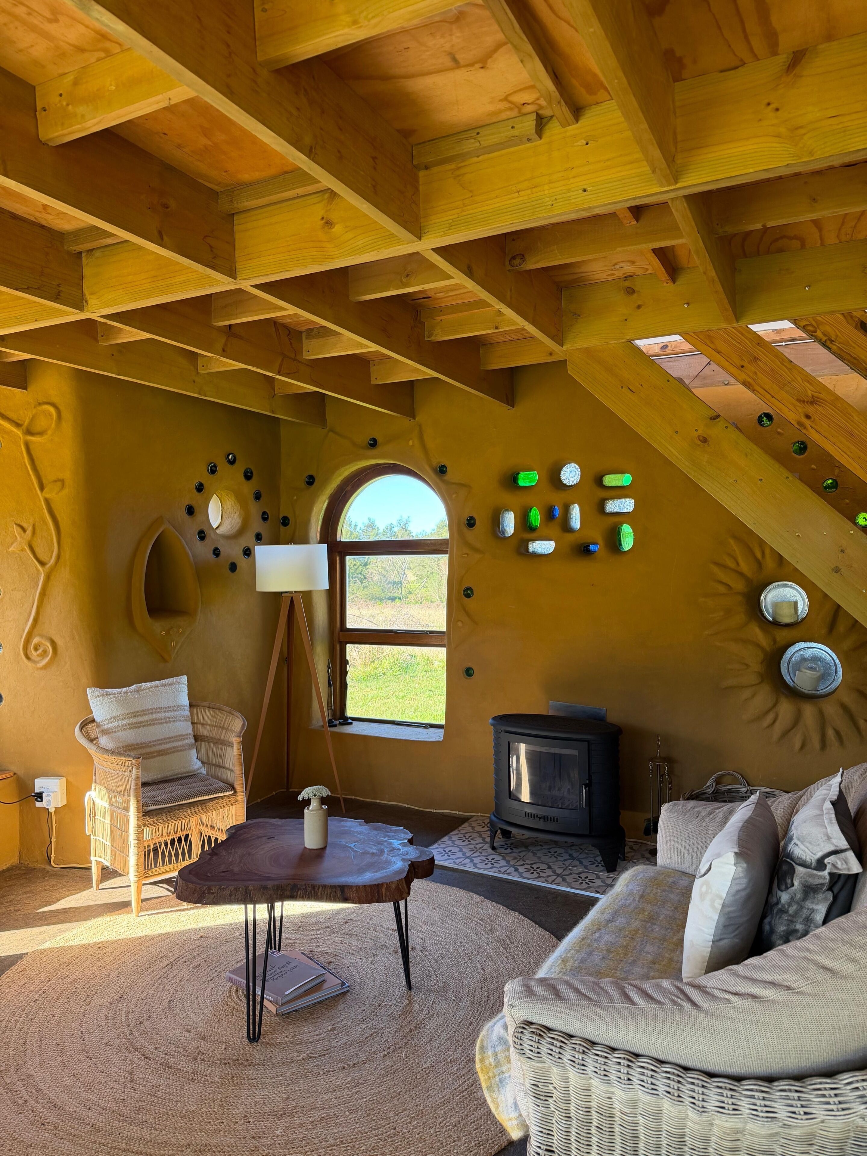 Una habitación acogedora con techo alto, chimenea, sofá de mimbre y decoración rústica de madera.