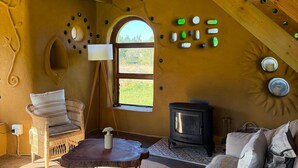 A cozy room with a high ceiling, a fireplace, a wicker sofa, and a rustic wooden interior.