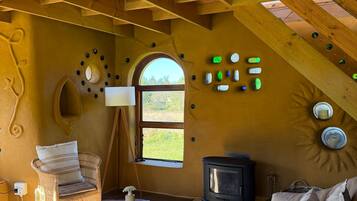 Une pièce chaleureuse avec un plafond haut, une cheminée, un canapé en osier et un intérieur en bois rustique.