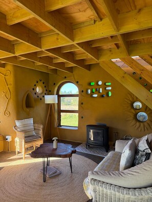A cozy room with a high ceiling, a fireplace, a wicker sofa, and a rustic wooden interior.