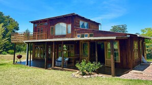 A two-story wooden house with a covered porch and a deck.