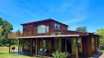 Une maison en bois à deux étages, dotée d’un porche abrité et d’une terrasse.