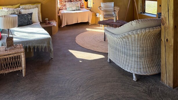 A cozy room with a bed, a wicker chair, and a small table.