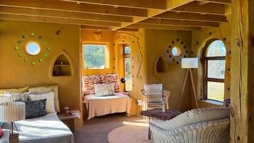 Une pièce confortable avec un lit, un fauteuil en osier et une petite table.
