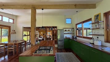 Une cuisine spacieuse avec des poutres en bois, un îlot central et des armoires vertes.