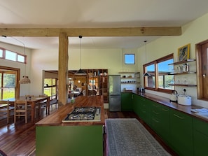 A spacious kitchen with wooden beams, a central island, and green cabinets.