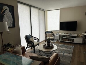 A living room with a sofa, two armchairs, a coffee table, a flat-screen TV, and a bookshelf. - NEW LISTING - 1 bedroom condo in FMB on the 7th floor with direct gulf views. (Fort Myers Beach)