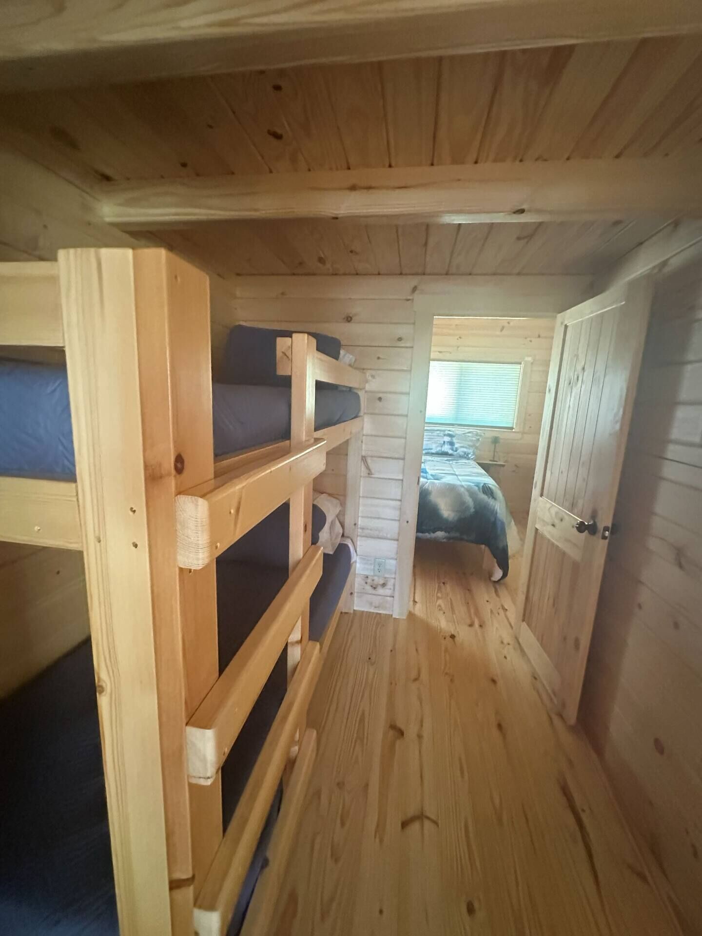 Una cabaña de madera con literas y una cama individual.