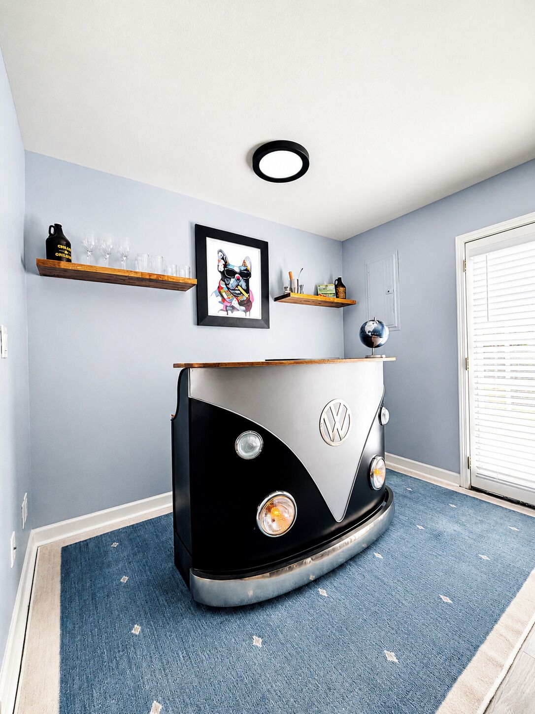 Um quarto com uma van VW camper como peça central, um quadro na parede e um globo em uma prateleira.