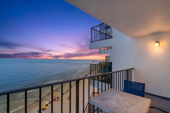 A balcony with a view of the beach and ocean during sunset. - Oceanfront Condo with Resort Pool, Hot Tub and Indoor Pool — Garden City Beach, (Garden City Beach)