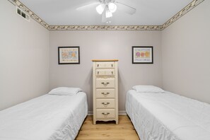 Ein Schlafzimmer mit zwei Einzelbetten, einem Schminktisch und zwei gerahmten Bildern an den Wänden.
